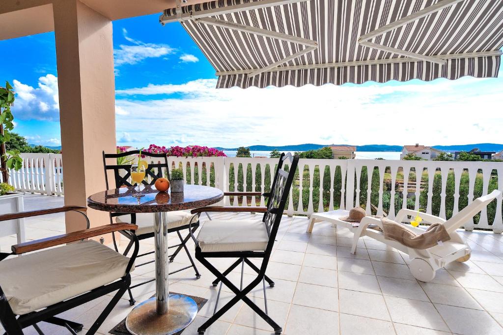 een patio met een tafel en stoelen op een balkon bij Apartments Anđelka in Bibinje