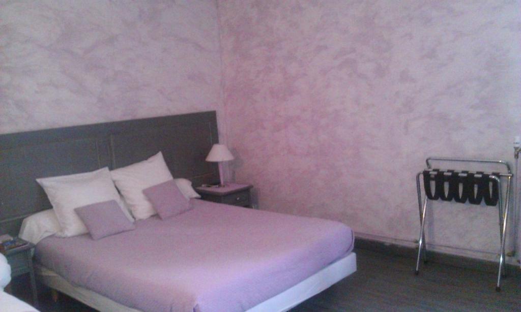 a bedroom with a bed and a pink wall at HOTEL RESTAURANT LE SAINT PIERRE "Grand Périgueux" in Saint-Pierre-de-Chignac