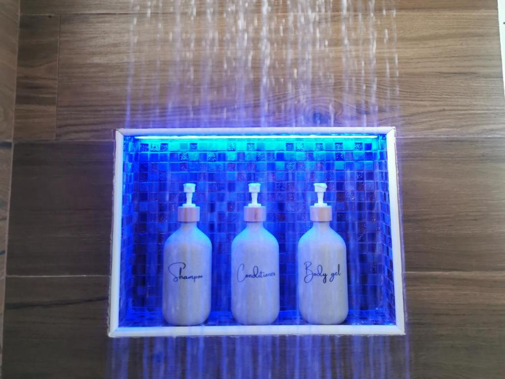 a group of four white bottles on a blue tile at Il Vialetto in Elmas