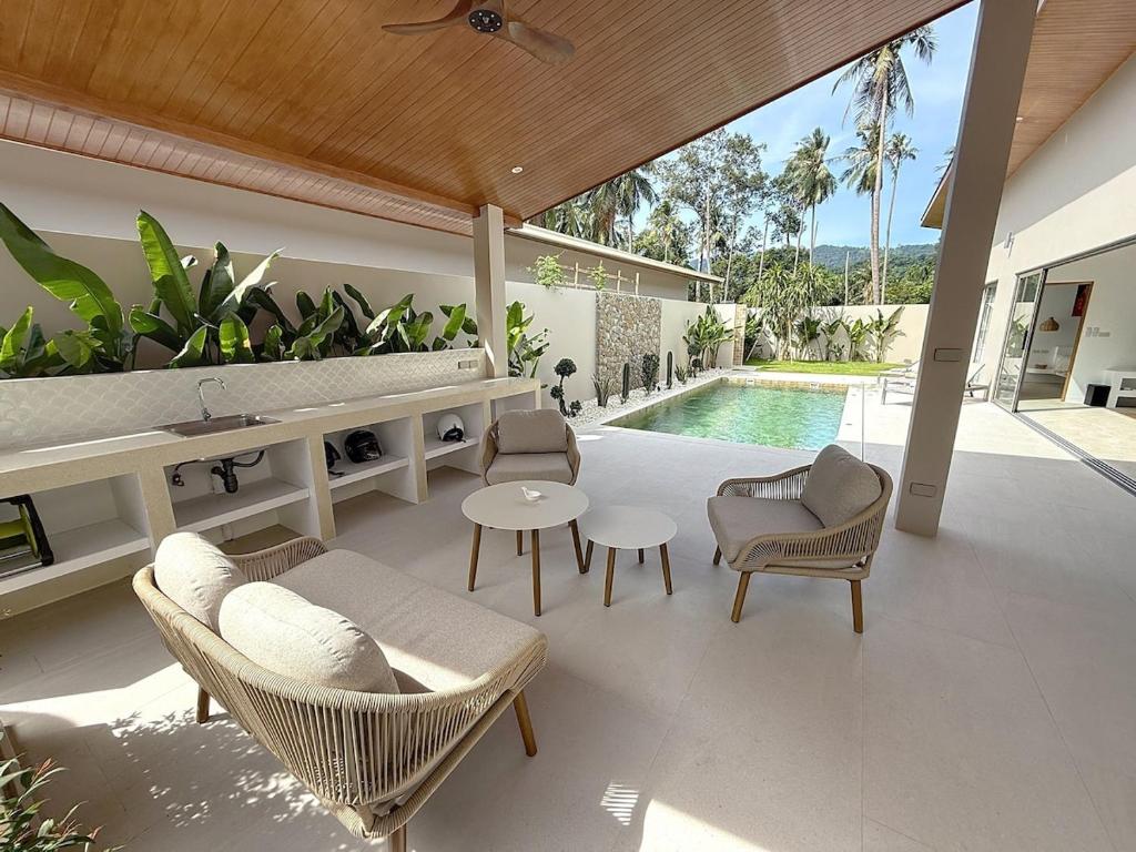 a patio with chairs and a table and a pool at Villa Panad 3BR Balinese Style in Amphoe Koh Samui