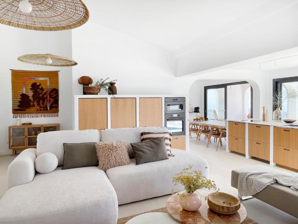 a living room with a white couch and a kitchen at NEW villa - luxury, views, hot tub, pool, 8 plus sofabed in Cómpeta