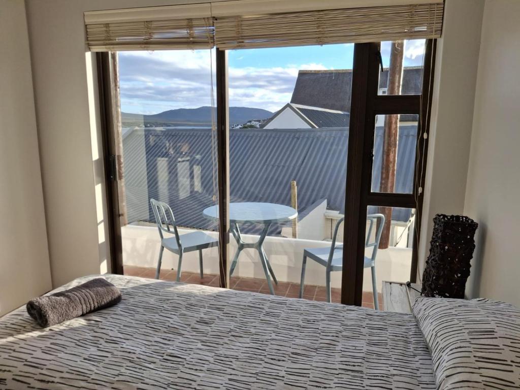 a bedroom with a bed and a view of a balcony at Little Anchor - Bachelor Flat in Witsand