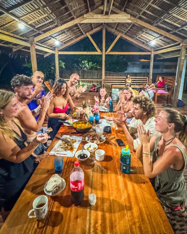 卢纳将军城Sunset Surf Hostel Siargao的一群人围坐在木桌旁