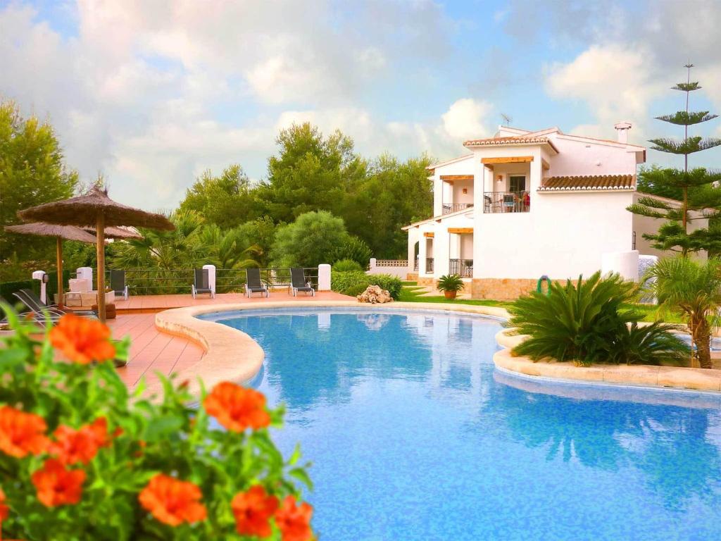 a swimming pool in front of a house with flowers at Apartments Benimeit in Moraira