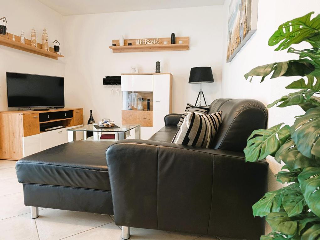 a living room with a leather couch and a television at Residenz Strandkrone 02 in Kühlungsborn