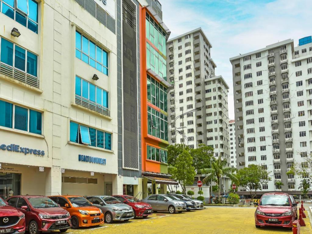 a parking lot with cars parked in front of tall buildings at OYO 90484 Bright Hotel in Sungai Way