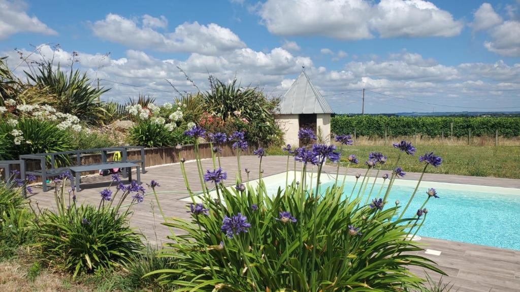 a garden with a swimming pool and purple flowers at Maison spacieuse proche de Saint-Emilion in Ruch