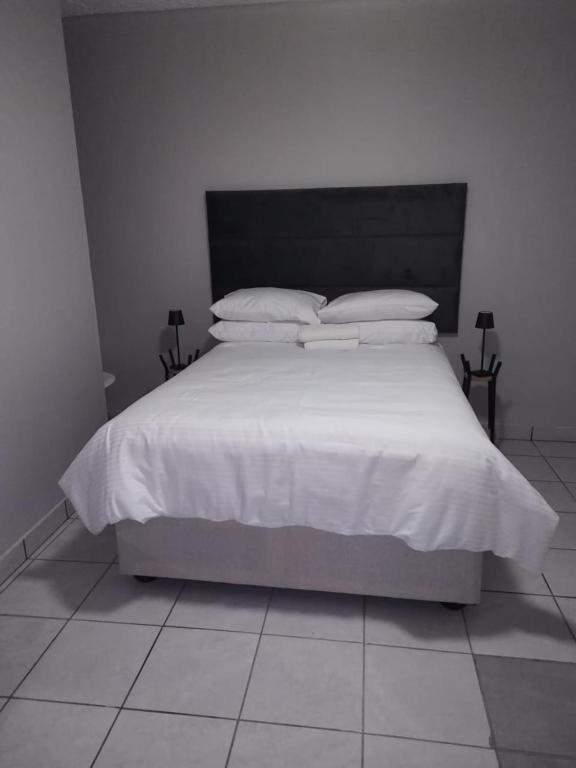 Un dormitorio con una cama con sábanas y almohadas blancas. en Grace Villas 5, en East London