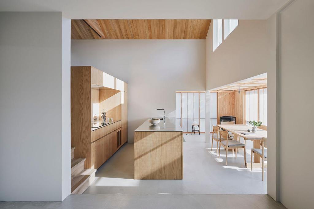 a kitchen and dining room with wooden cabinets and a table at SANU 2nd Home SAZARENO 下田 in Shimoda