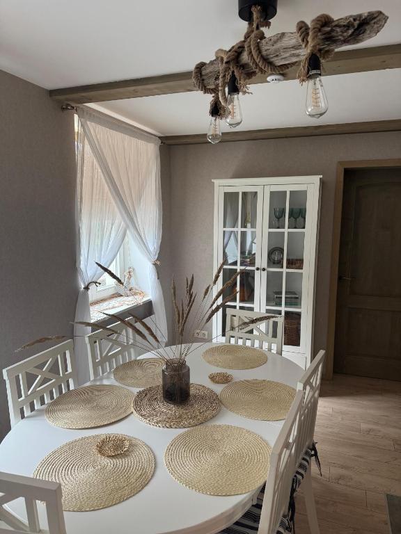a white table with four chairs and a dining room at Dzintarielas Miera Osta in Pāvilosta