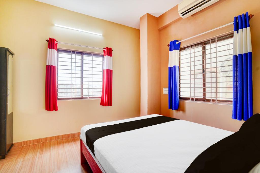 a bedroom with red and blue curtains and a bed at Hotel O PALMS INN ELEGANT STAY in Bengaluru