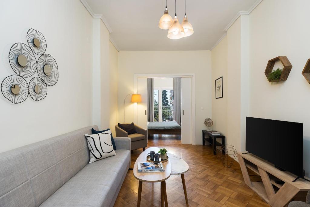 Una sala de estar con un sofá y un televisor. en Houseloft Queen Olga Casa, en Tesalónica