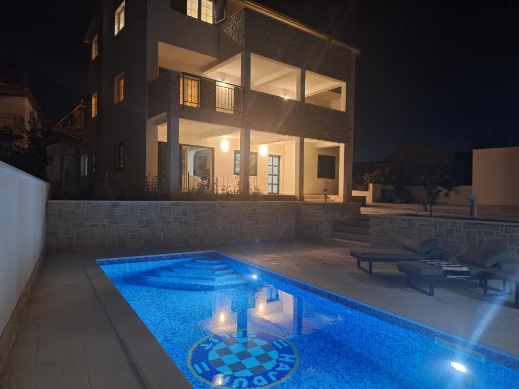 a swimming pool in front of a house at night at Apartmani Jerka in Vinišće