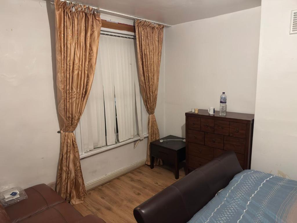 a bedroom with a window with a couch and a dresser at Pdmdecor House in Hunslet