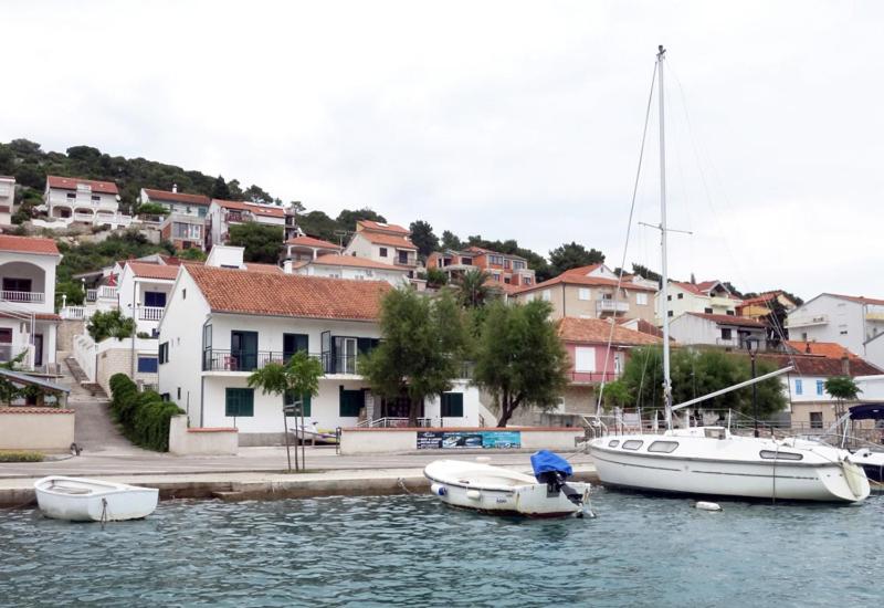 two boats are docked in the water next to houses at Waterfront Apartments in Tisno