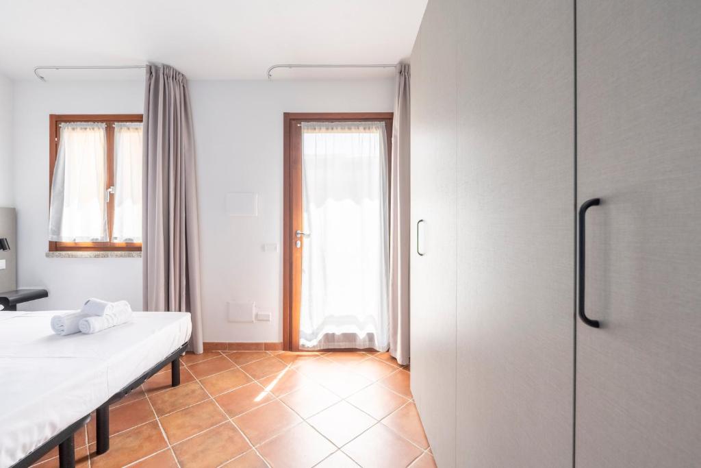 Cette chambre blanche comprend un lit et un réfrigérateur. dans l'établissement Residence Rocce Rosse, à Isola Rossa