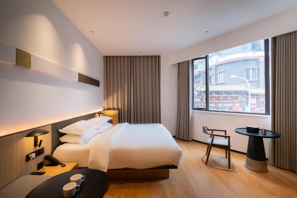 a hotel room with a bed and a desk and a window at SFEEL设计师酒店Designer Hotel乐山大佛上中顺店 in Leshan