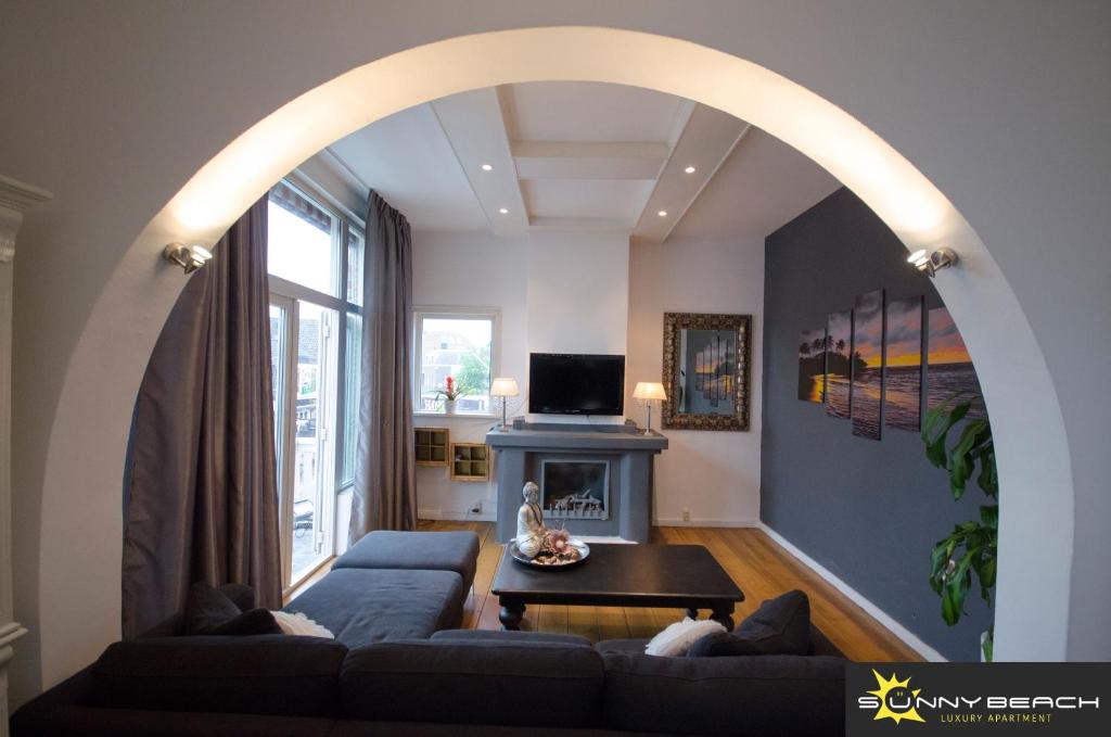 an archway in a living room with a couch and a fireplace at SunnyBeach Luxury apartment in Zandvoort