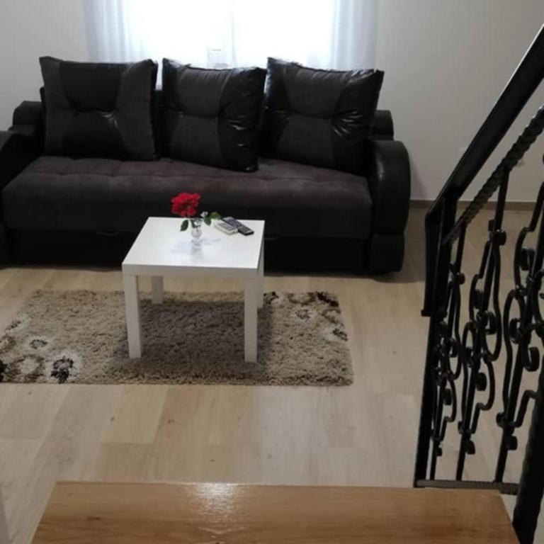 a living room with a black couch and a white coffee table at Apartmani Ana S in Vrnjačka Banja