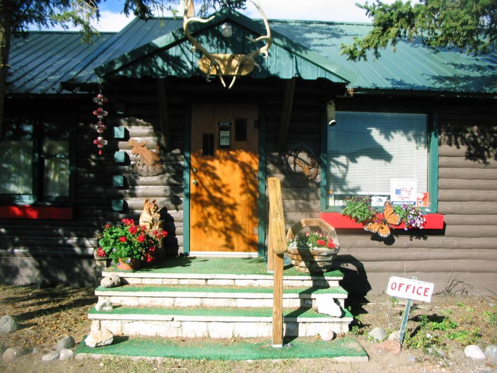 una pequeña casa con un perro sentado en el porche delantero en South Fork Lodge & RV Park Colorado, en South Fork