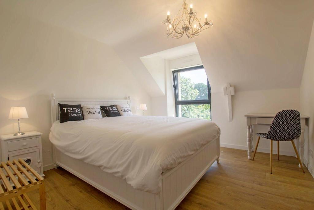 Un dormitorio blanco con una cama grande y una lámpara de araña. en Le clos du guern, en Ploeren