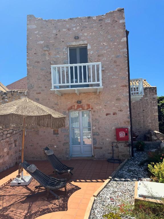 a building with two chairs and an umbrella at Balcony&Tower in Areopoli