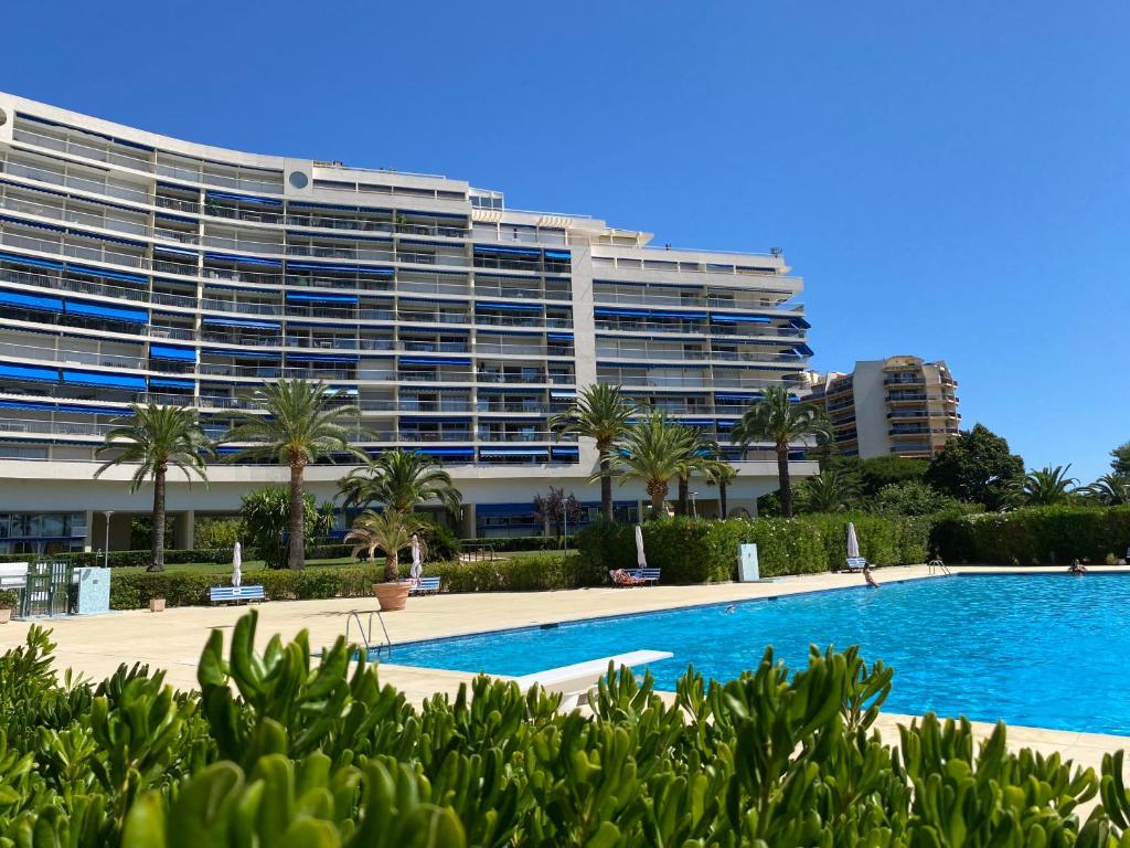 un grand bâtiment avec une piscine en face d'un bâtiment dans l'établissement Studio Cannes Marina - port Mandelieu, à Mandelieu-la-Napoule
