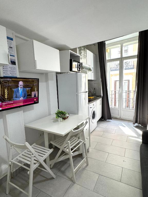 kuchnia ze stołem i telewizorem na ścianie w obiekcie Acogedor apartamento exterior con balcón en el Barrio de Chueca, Gran Vía con aire acondicionado w Madrycie