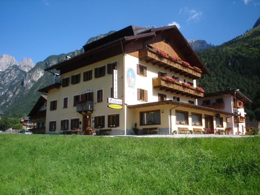 Ein großes Gebäude auf einem Hügel mit Bergen im Hintergrund in der Unterkunft Hotel GALENO - 3 Cime Vista - in Auronzo di Cadore