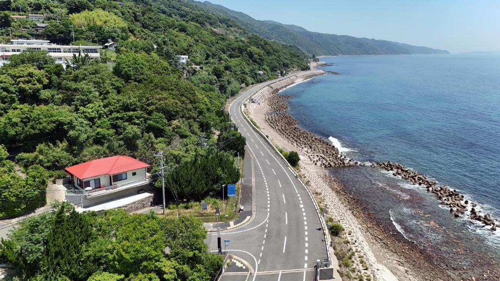a road next to a beach with a red roof at La maison du sud d'awaji - Ocean View Private Villa in Minamiawaji