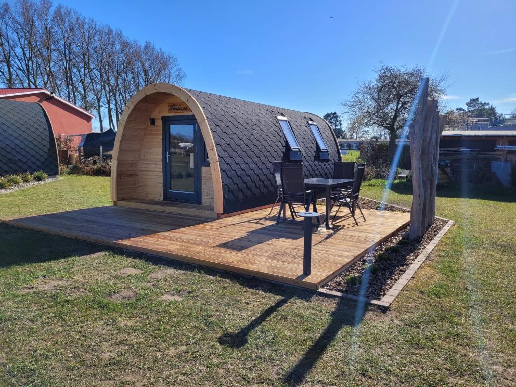 佩佩洛Ostseecamping am Salzhaff的小屋在甲板上配有桌椅