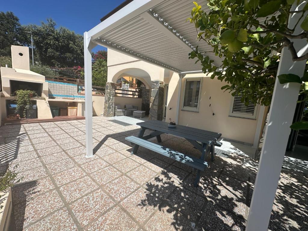a patio with a picnic table under a white pergola at Casa Cioppy in Cala Gonone