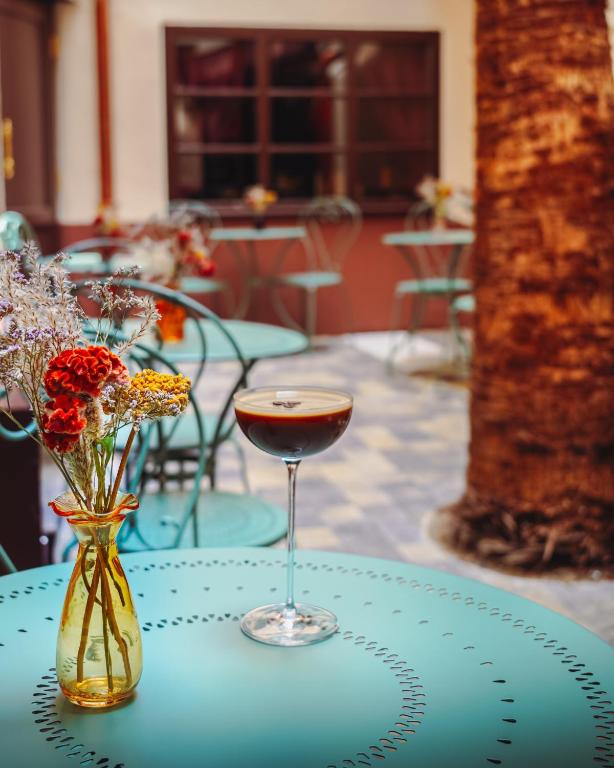 a table with a glass of wine and a vase of flowers at Madame C - Hôtel Particulier in Strasbourg