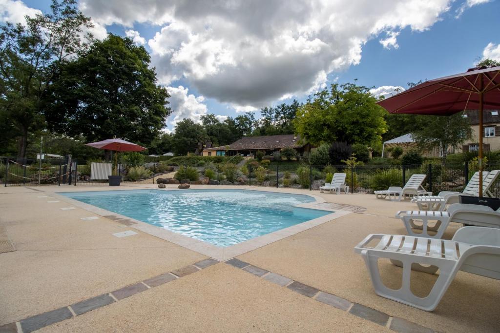 - une piscine avec des chaises blanches et un parasol dans l'établissement Mobilhome La Truffière, à Saint-Pompont