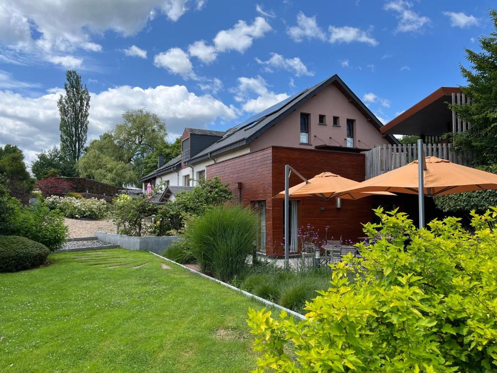 a house with an umbrella in a yard at Hostellerie du Peiffeschof, The Originals Relais in Arlon
