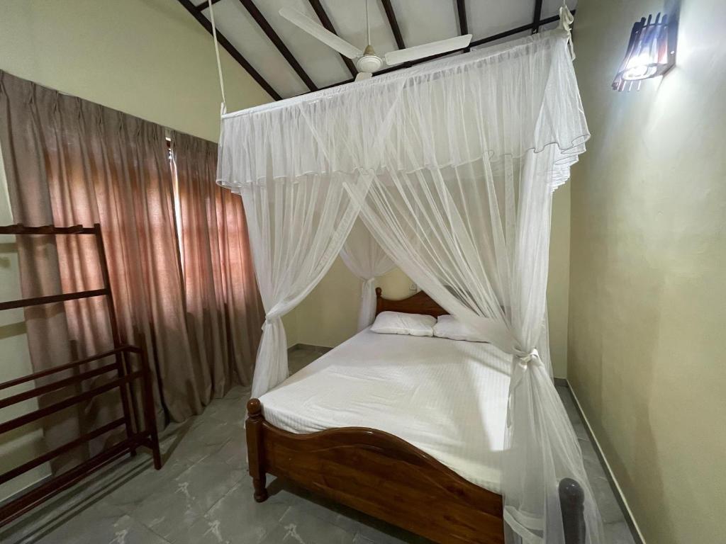 Un dormitorio con una cama con dosel y cortinas blancas. en Three Brothers Villa, en Mirissa