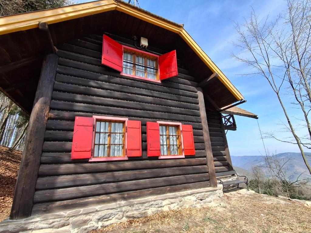 a log cabin with red shutters and mountains in the background at Waldpoesie - Das Wald-Cottage in Benking