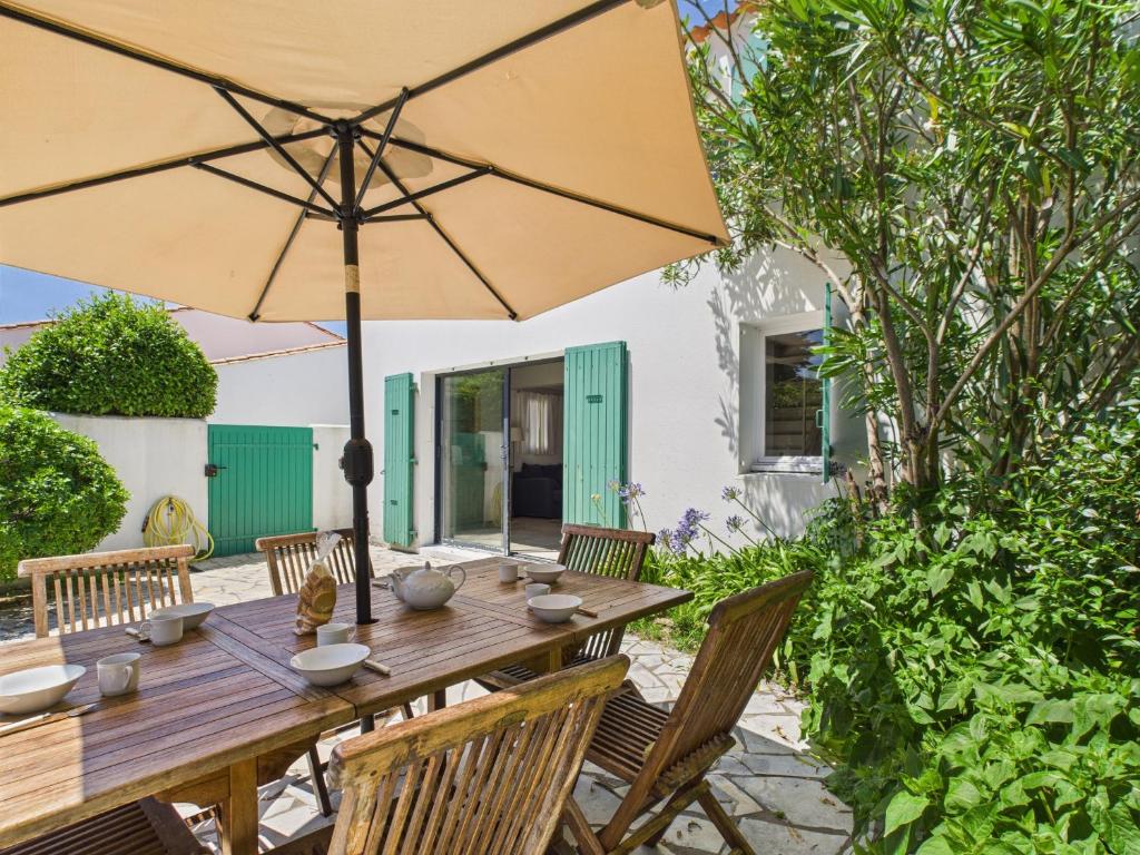 a wooden table with an umbrella on a patio at Saint Clément - 400 m plage - Cœur village in Saint-Clément-des-Baleines