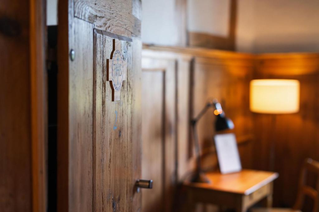 una porta in legno in una stanza con tavolo e lampada di Klosterherberge Solothurn Self Check-in a Solothurn