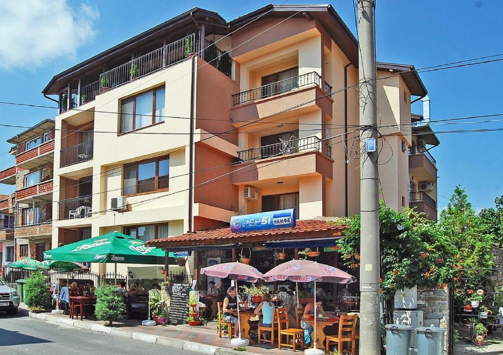 a building with tables and umbrellas in front of a building at Dimitur Jekov Guest House in Obzor