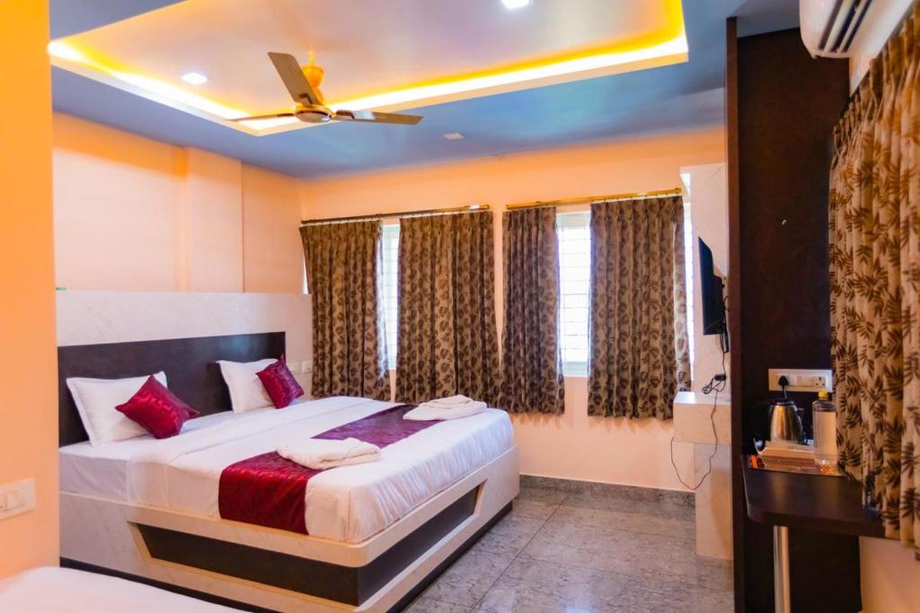 a bedroom with a large bed with red pillows at Hotel Mysuru Haven in Mysore