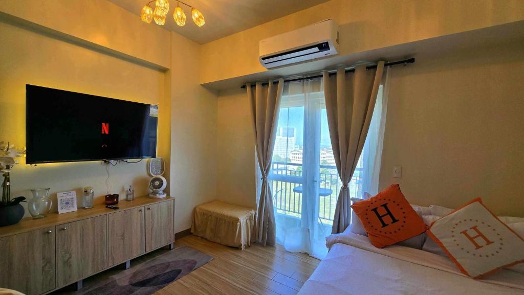 a living room with a tv and a bed and a window at Homestayed ilo in Iloilo City