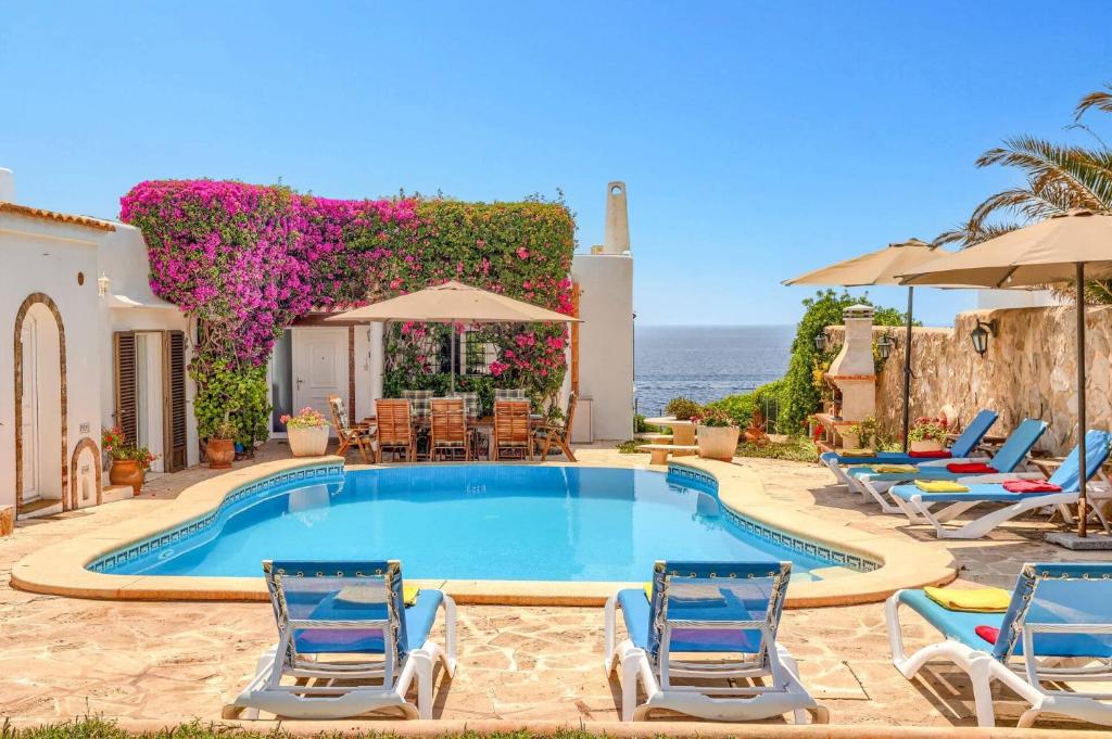 una piscina con sedie e l'oceano sullo sfondo di Villa Ariet by Villa Plus a Felanitx