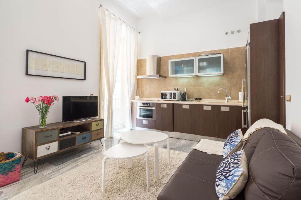 Plaza Picasso في مالقة: غرفة معيشة مع أريكة ومطبخ