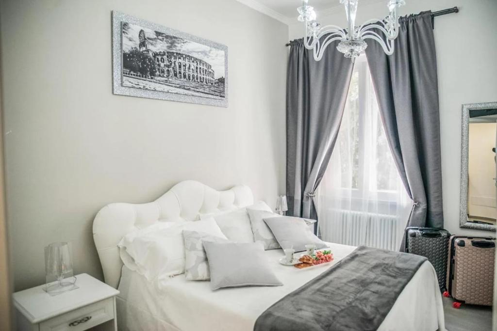 a bedroom with a white bed and a chandelier at Central Luxury Apartment in Lido di Ostia