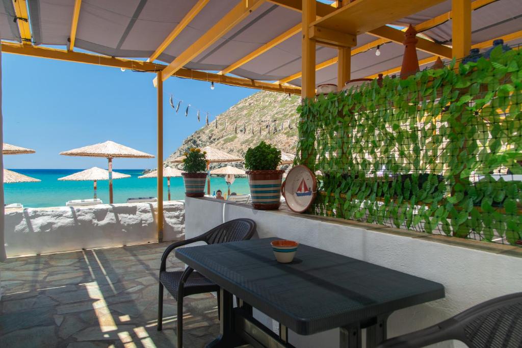 a table and chairs on a patio next to the beach at Green Bay Studio 1 in Sifnos