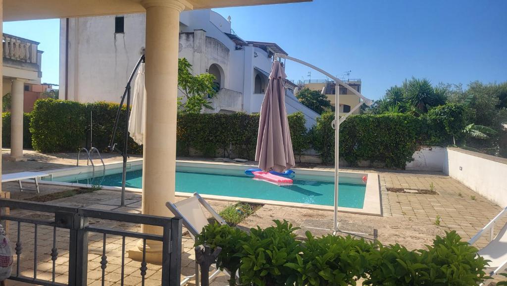a swimming pool with an umbrella next to a building at Apartment Gaia in Nardò