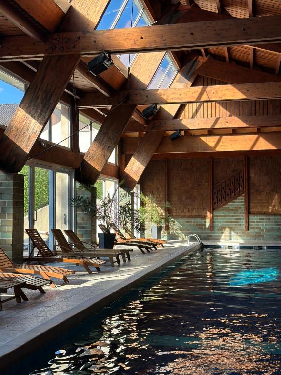 une piscine avec des bancs et un plafond en bois dans l'établissement Hotel Les Vallées Labellemontagne, à La Bresse