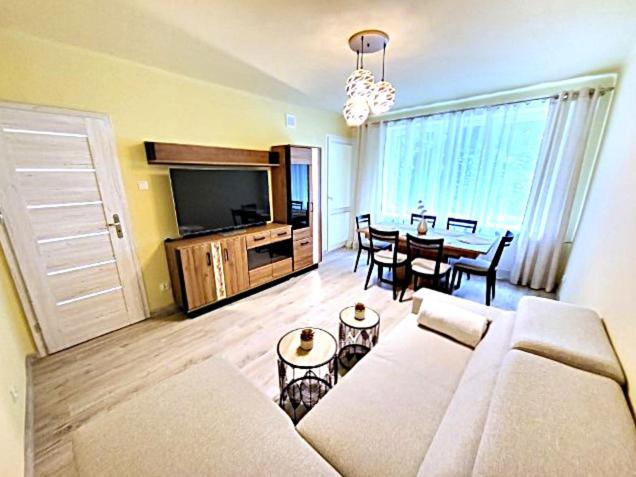 a living room with a couch and a dining room at Apartament Rodzinny Młyńska in Augustów