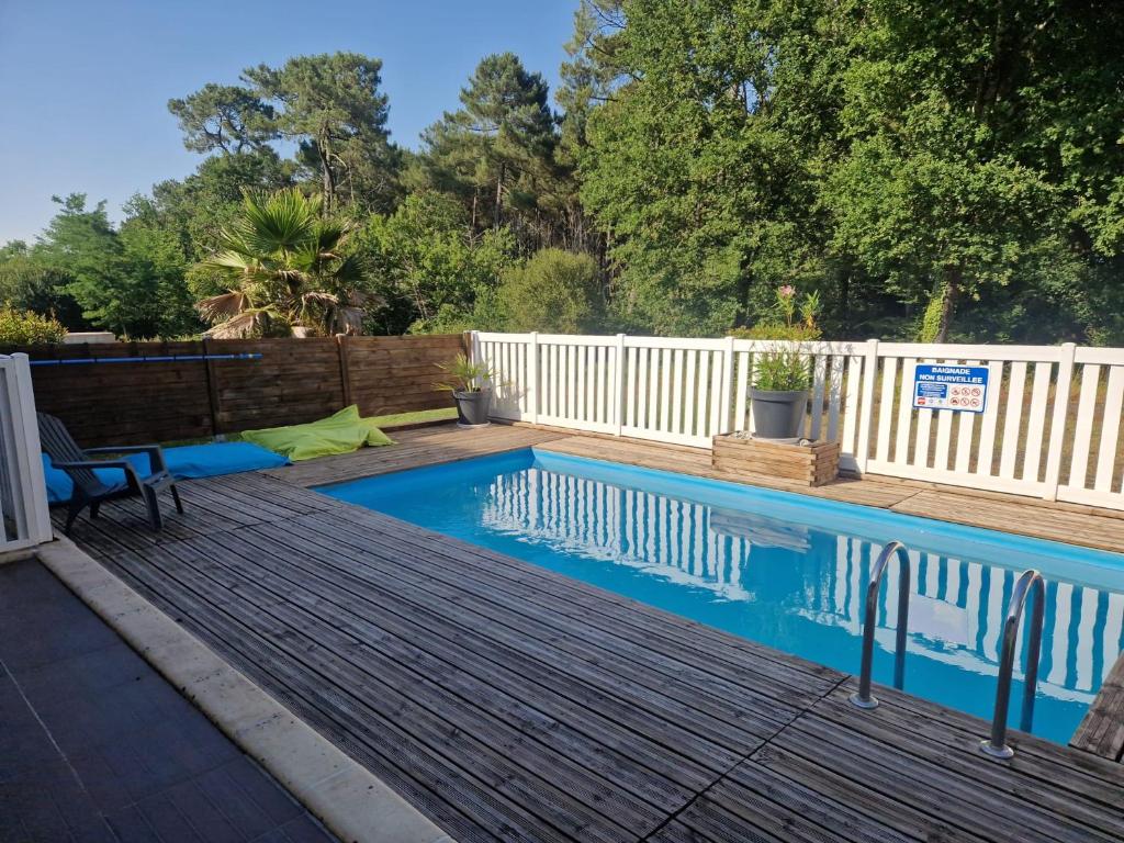 a swimming pool with a wooden deck and a white fence at Le Nid Cabailla in Coimères